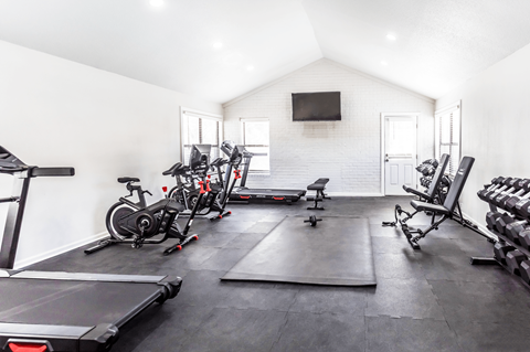 A home gym with a treadmill, exercise bikes, and weights.