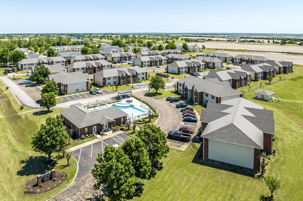 A bird's eye view of a residential area with houses, a swimming pool, and a parking lot.