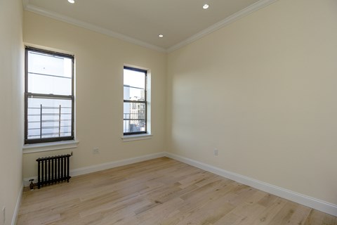 A room with wooden floors and two windows.