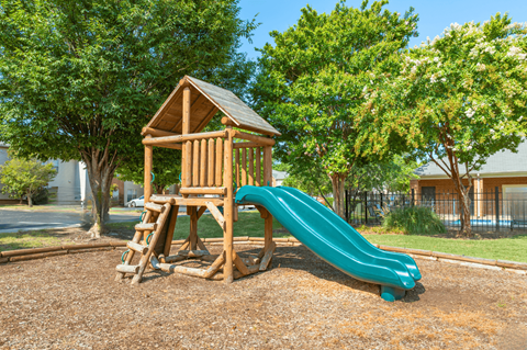 A wooden playground structure with a green slide.