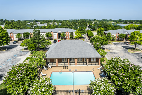 A swimming pool is surrounded by a pavilion and trees.