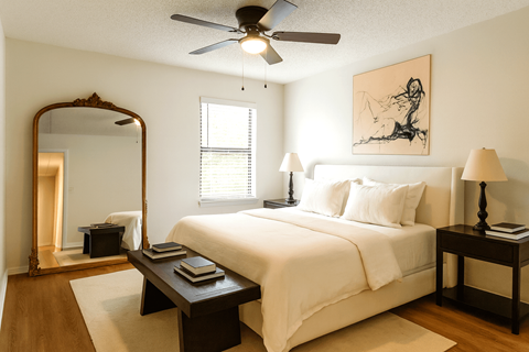 A bedroom with a large bed, a mirror, and a ceiling fan.