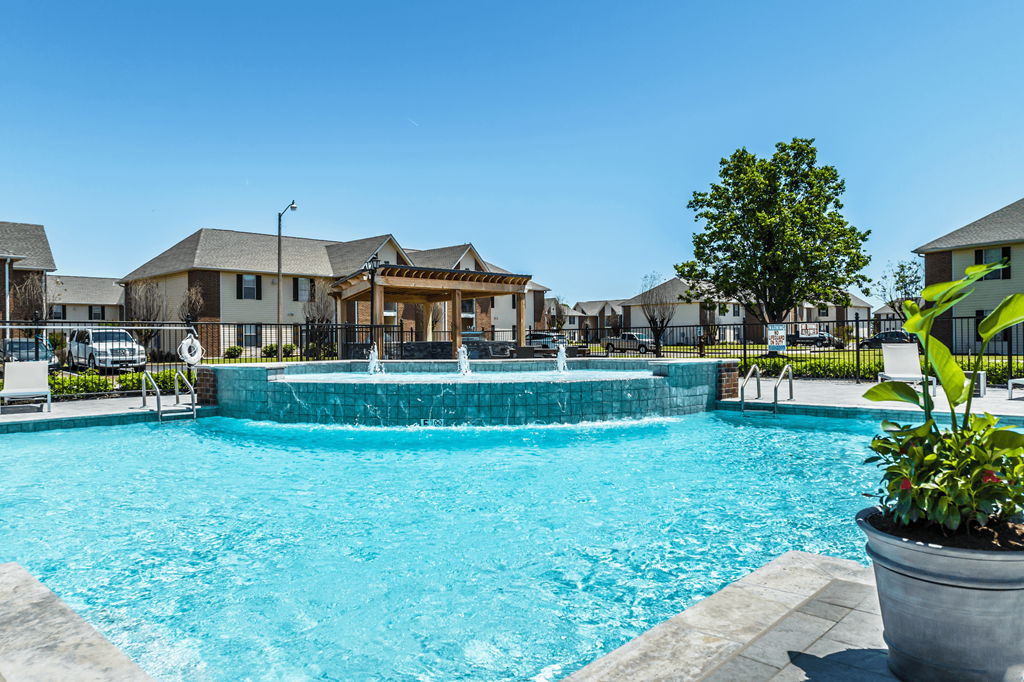A large swimming pool with a waterfall and a building in the background.
