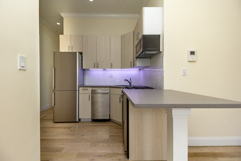 A kitchen with a refrigerator, stove, and trash can.