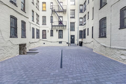 A long, narrow courtyard between two buildings with a fire escape on the side.