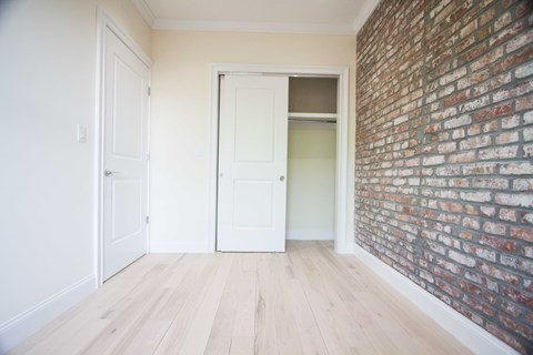 A room with a white door and a brick wall.