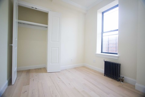 Empty room with a window and a radiator on the floor.