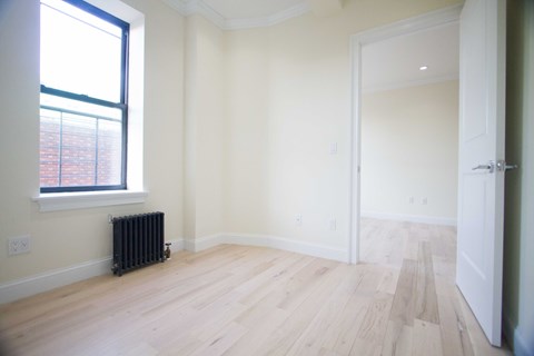 A room with a window and a radiator on the floor.