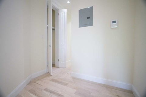 A room with a door and a wall-mounted thermostat.