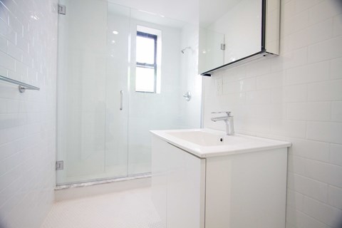 A white sink in a white tiled bathroom.