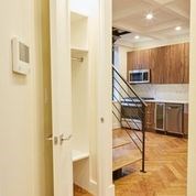 A white door is open to a kitchen and staircase.