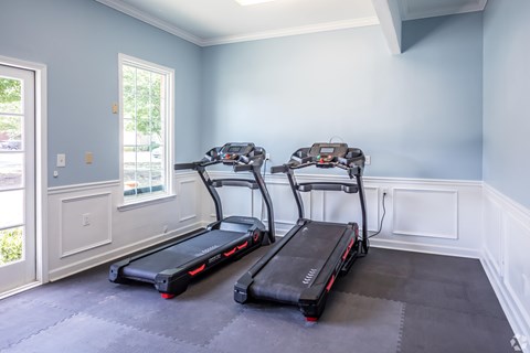 Two treadmills in a room with light blue walls.