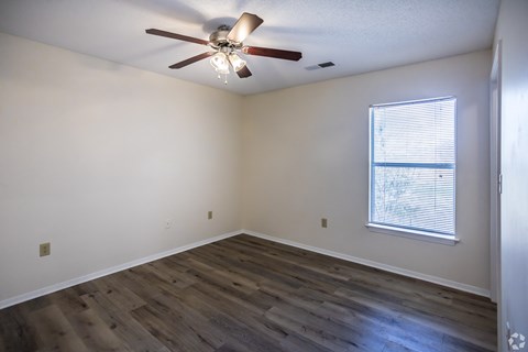 A room with a ceiling fan and a window with blinds.
