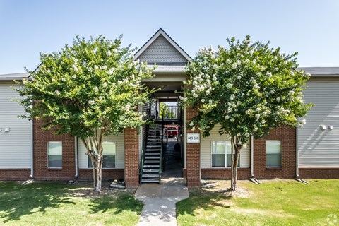A small building with a front porch and a tree in front.