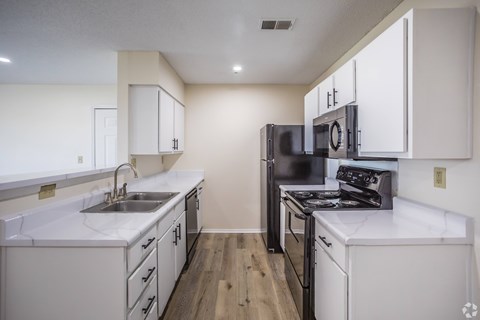 A kitchen with black appliances and white cabinets.