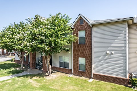 A tree with white flowers is in front of a brick house.