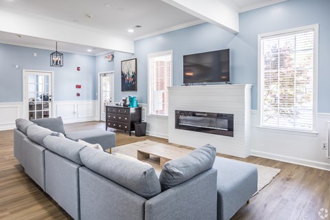 A grey couch sits in a living room with a fireplace and a television.