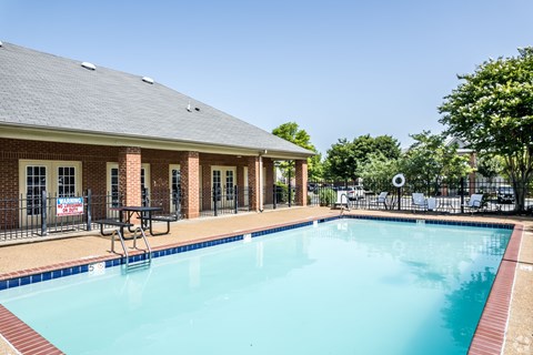 A pool in front of a brick building with a sign that says "No Swimming".