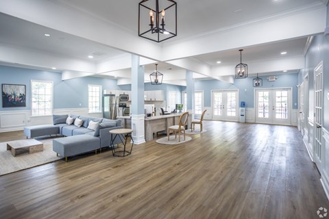 A spacious living room with a grey sofa and wooden floors.