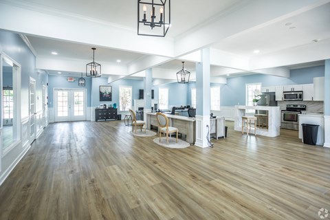 A spacious kitchen and living room with wooden floors and white walls.