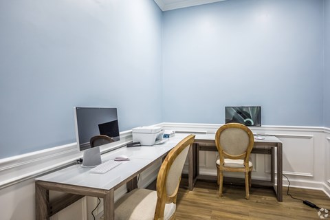 A desk with a laptop and a monitor with a chair in front of it.