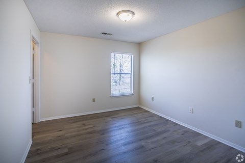 A room with a window and wooden flooring.