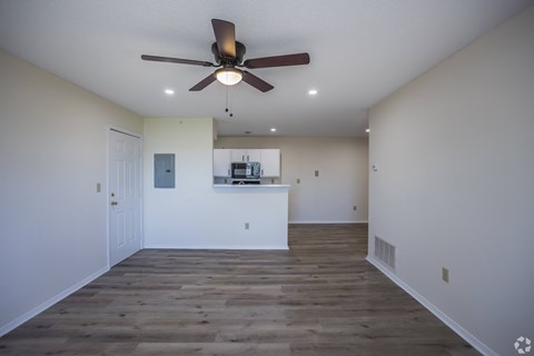 A room with a ceiling fan and wooden flooring.