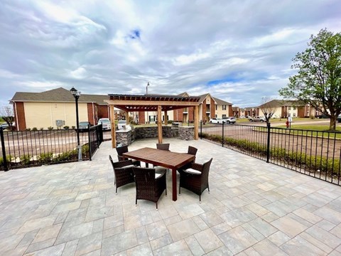 A patio with a table and chairs is surrounded by a black fence.