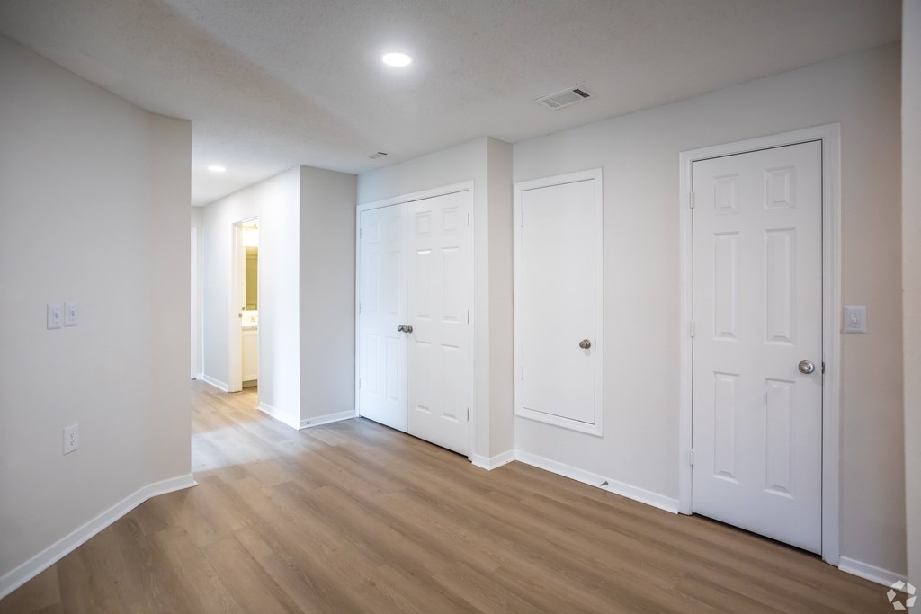 A long hallway with white doors and wood floors.