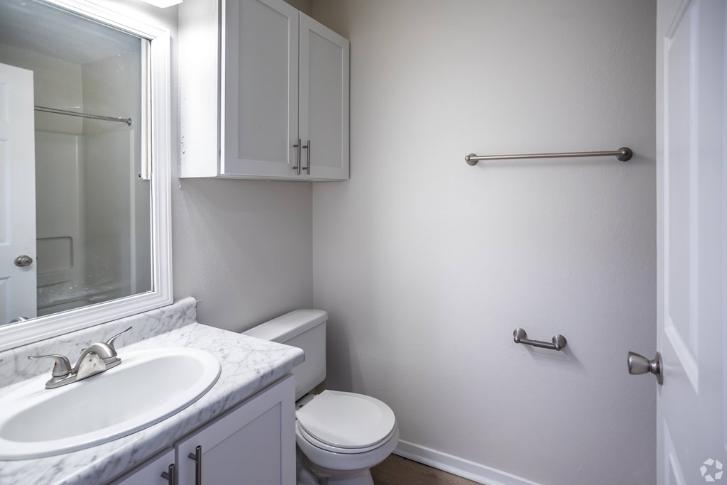 A white bathroom with a toilet, sink, and towel rack.