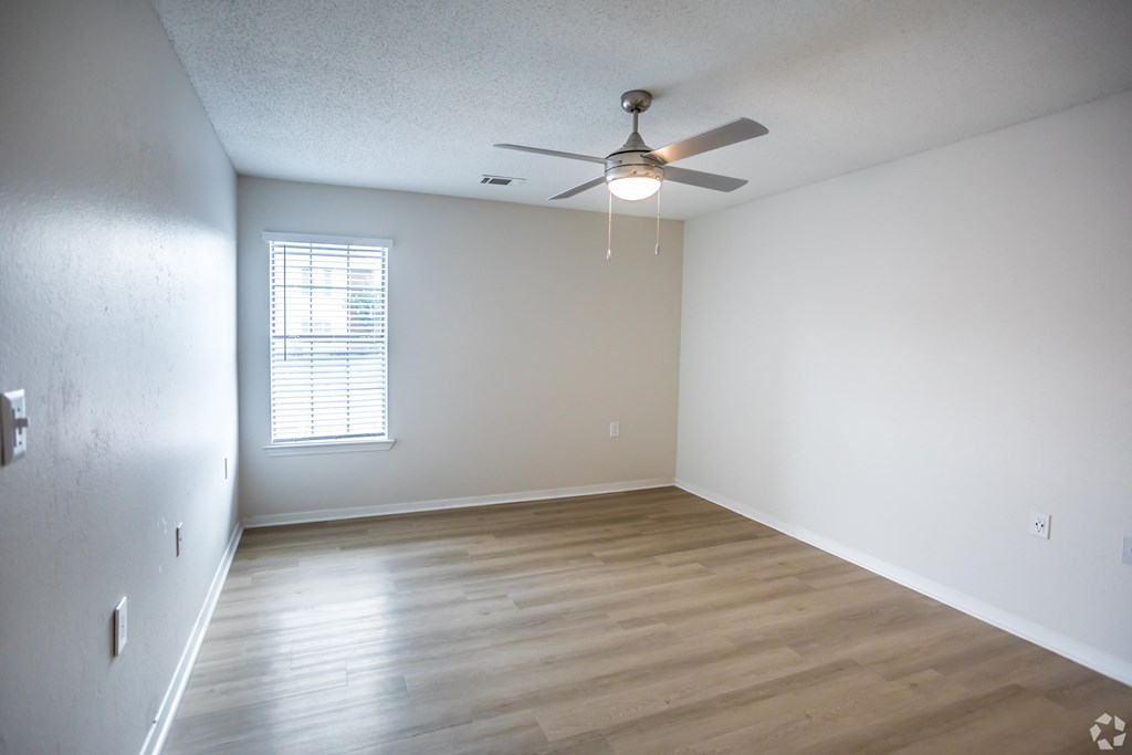 A room with a ceiling fan and a window with blinds.