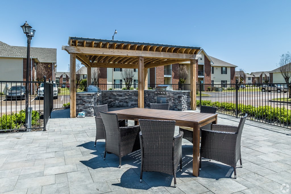 A patio with a table and chairs under a wooden pergola.