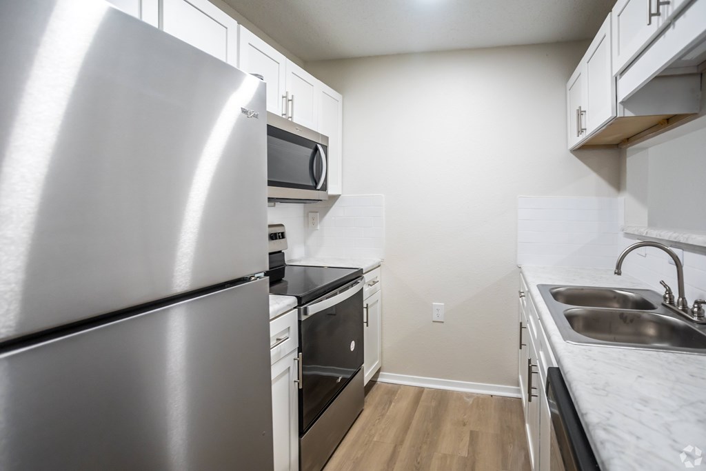 A kitchen with a stainless steel refrigerator, microwave, oven, and sink.
