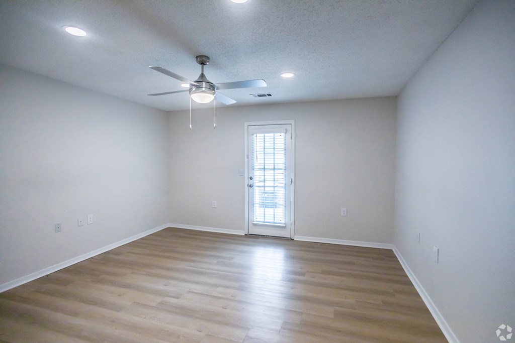 A room with a ceiling fan and wooden flooring.