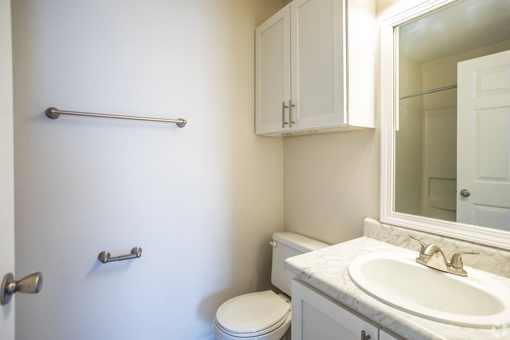 A white bathroom with a toilet, sink, and towel rack.