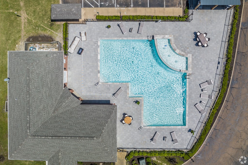 An aerial view of a swimming pool surrounded by a grassy area and a building.