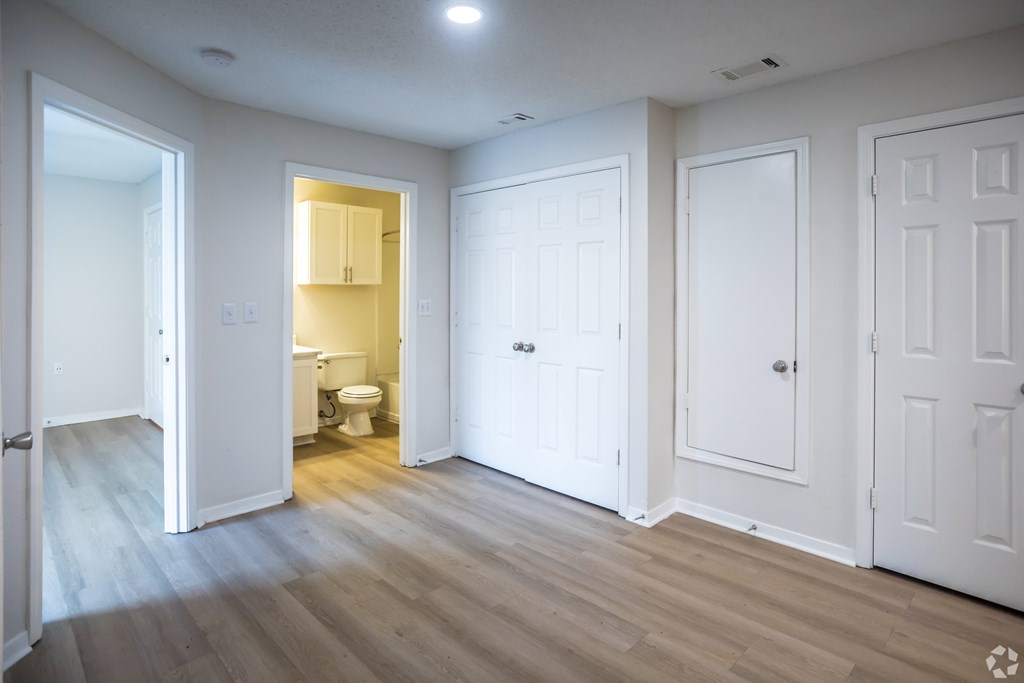 A white bathroom with a toilet and sink is visible through an open door.