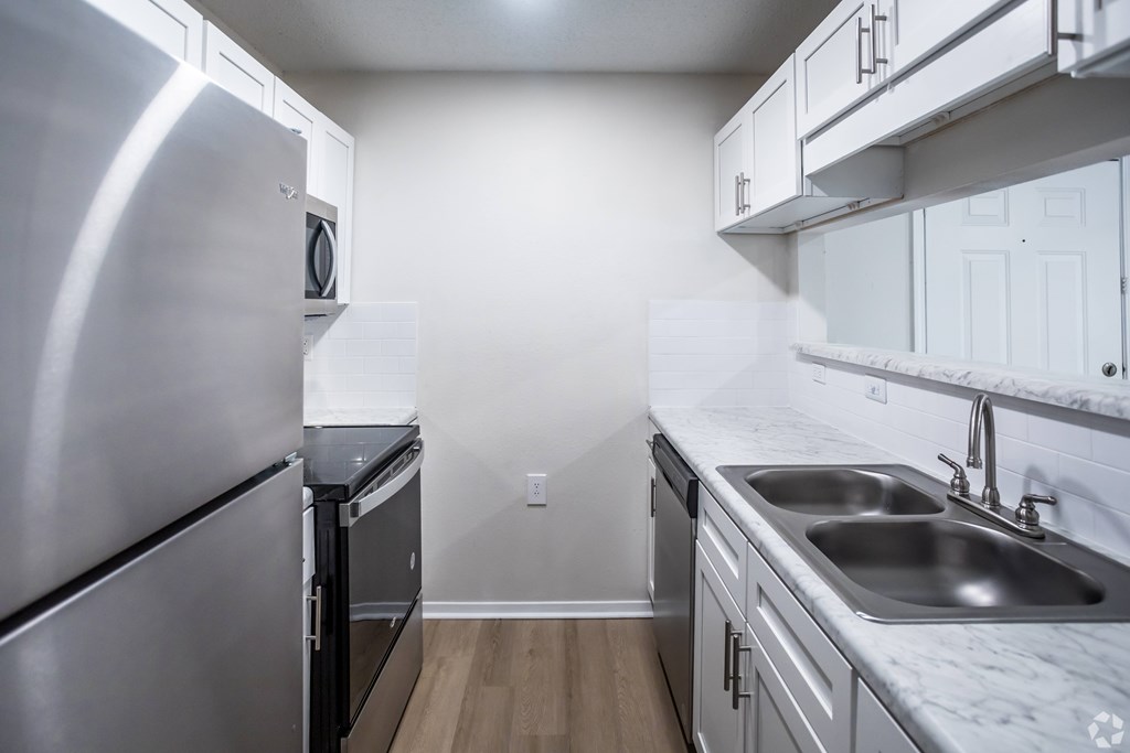 A kitchen with a stainless steel refrigerator and a marble countertop.