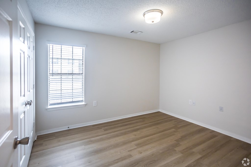A room with a window and wooden floors.