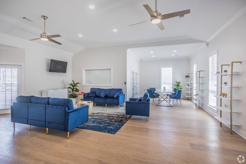 A living room with a blue sofa and a television on the wall.