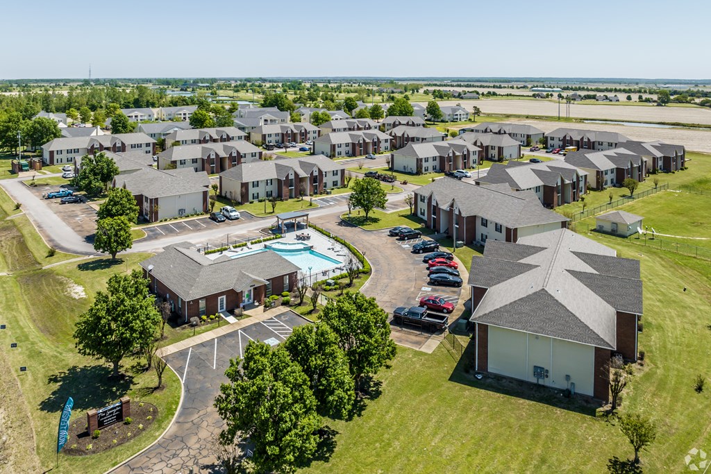 A bird's eye view of a residential area with houses, cars, and a swimming pool.