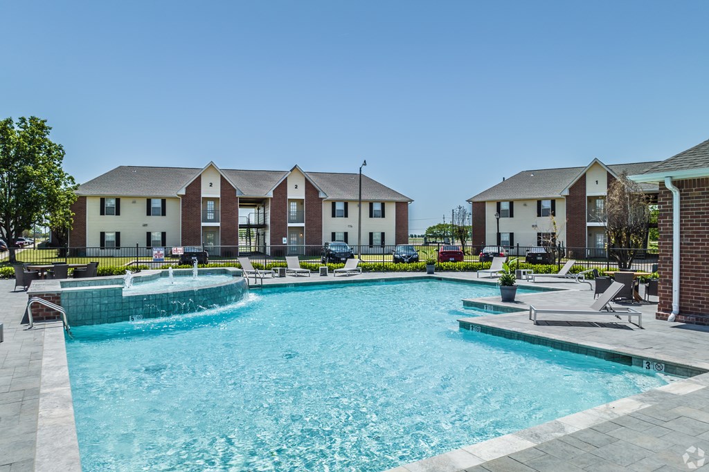 A swimming pool in front of a building with a clear blue sky.
