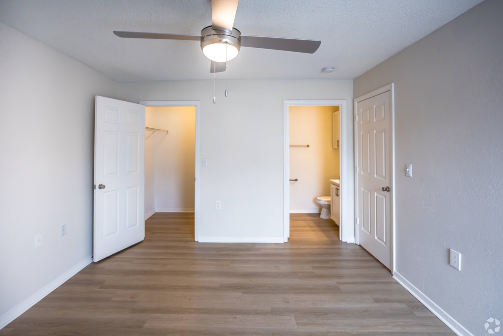 A room with a ceiling fan and wooden floors.