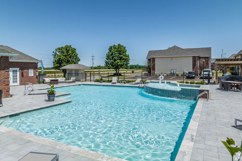 A large swimming pool with a glass enclosure and a hot tub.