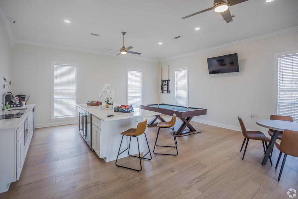 A kitchen with a pool table and a television.