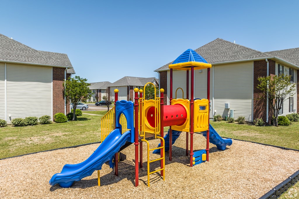 A playground with a blue slide and a red and yellow structure.