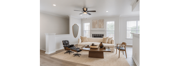 A living room with a white couch, a brown coffee table, and a black chair.