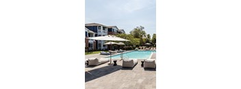 A pool area with a row of lounge chairs and umbrellas.