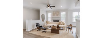 A living room with a white couch, a brown coffee table, and a black chair.