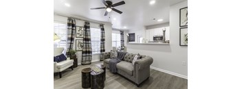 A living room with a grey couch, a white chair, and a wooden coffee table.